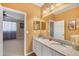 Bathroom features a double sink vanity with granite countertops and decorative mirror at 5700 Bentgrass Dr # 209, Sarasota, FL 34235