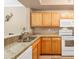 Well-maintained kitchen boasts wood cabinetry, granite countertops, and modern white appliances at 5700 Bentgrass Dr # 209, Sarasota, FL 34235