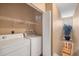 Functional laundry room with washer, dryer, storage shelves, and staircase access at 5700 Bentgrass Dr # 209, Sarasota, FL 34235