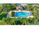 An aerial view of the community pool complete with a slide, lounge chairs, and lush landscaping with palm trees at 6156 41St E St, Bradenton, FL 34203