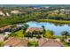An aerial view of a single-Gathering home next to a serene lake, surrounded by mature trees and landscaping at 629 River Enclave Ct, Bradenton, FL 34212