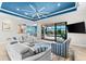 Spacious living room with blue ceiling, ceiling fan, large sectional, and sliding glass doors to the outdoor pool at 629 River Enclave Ct, Bradenton, FL 34212