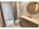 Well-lit bathroom featuring a marble tiled shower/tub combination, a vanity, and a round wood-framed mirror at 750 N Tamiami Trl # 604, Sarasota, FL 34236