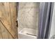 View of a tub/shower combo with a marble tile surround, partially obscured by a wooden barn door at 750 N Tamiami Trl # 604, Sarasota, FL 34236