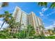 A tall luxury building is surrounded by lush green palm trees and landscaping at 750 N Tamiami Trl # 604, Sarasota, FL 34236