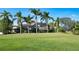 Spacious backyard with lush green lawn and mature palm trees view of home at 8025 Via Fiore, Sarasota, FL 34238