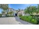A beautifully landscaped home featuring a circular driveway, mature trees, and manicured shrubbery at 8025 Via Fiore, Sarasota, FL 34238