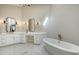 Bright main bathroom with freestanding tub, dual sinks, marble floors, and decorative lighting at 8025 Via Fiore, Sarasota, FL 34238
