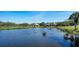 A picturesque pond is surrounded by lush landscaping and mature trees in a residential neighborhood at 8025 Via Fiore, Sarasota, FL 34238