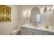 Stylish powder room featuring a gray vanity with modern fixtures and an arched mirror with sconces at 8025 Via Fiore, Sarasota, FL 34238