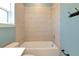 This bathroom features a tub, shower, light tile surround, and a blue accent wall at 8262 Velda Trl, Sarasota, FL 34241