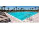 Large community pool with crystal-clear water, surrounded by ample lounging chairs and palm trees at 8262 Velda Trl, Sarasota, FL 34241