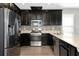 Modern kitchen with stainless steel appliances, dark cabinetry, stone backsplash, and quartz countertops at 8262 Velda Trl, Sarasota, FL 34241