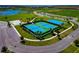 Aerial view of tennis and basketball courts with nearby athletic fields and beach volleyball in a vibrant community at 8262 Velda Trl, Sarasota, FL 34241