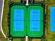 Aerial view of community tennis courts with vibrant blue surfaces and manicured green surroundings at 8262 Velda Trl, Sarasota, FL 34241