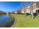 A view of pond and the house's exterior with a lush lawn at 8323 Enclave Way # 104, Sarasota, FL 34243