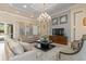 Well-decorated lounge area featuring comfortable seating, stylish chandelier, TV, and neutral color palette at 8323 Enclave Way # 104, Sarasota, FL 34243