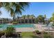 Community pool featuring palm trees, a tanning deck, and a building with shade for residents and guests at 8323 Enclave Way # 104, Sarasota, FL 34243