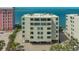 An exterior view of a condo building with a parking area and palm trees by the water at 97 Sunset Dr # 203, Sarasota, FL 34236