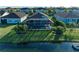 Aerial view showing screened lanai overlooking the lake with lush landscaping and a fountain feature at 13228 Saw Palm Creek Trl, Lakewood Ranch, FL 34211