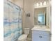 Compact bathroom features a shower with a decorative curtain, a toilet and a single sink vanity at 13228 Saw Palm Creek Trl, Lakewood Ranch, FL 34211