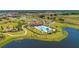 Aerial view of community pool and clubhouse surrounded by manicured lawns, a playground, and a walking path near a pond at 13228 Saw Palm Creek Trl, Lakewood Ranch, FL 34211