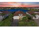 Aerial view of waterfront home with terra cotta roof, brick driveway, lush landscaping, and beautiful sunset at 13228 Saw Palm Creek Trl, Lakewood Ranch, FL 34211