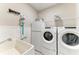 Functional laundry room with washer, dryer, utility sink, storage shelves, and vacuum cleaner at 13228 Saw Palm Creek Trl, Lakewood Ranch, FL 34211