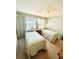 A bedroom featuring twin beds with leaf-patterned bedding, a large window, and neutral-toned carpeting at 1412 56Th W St # 1412, Bradenton, FL 34209