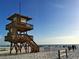 Three-story lifeguard tower made of natural wood overlooking a wide beach with people and an ocean view at 1412 56Th W St # 1412, Bradenton, FL 34209