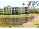 Bright yellow condo complex with tall palm trees overlooking a scenic pond at 2060 Willow Hammock Cir # 201, Punta Gorda, FL 33983