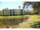 Bright, yellow condo building overlooking a tranquil pond, complemented by palm trees and lush green lawns at 2060 Willow Hammock Cir # 201, Punta Gorda, FL 33983
