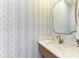 Stylish powder room featuring patterned wallpaper, a modern vanity with a gold faucet, and a decorative mirror at 215 83Rd St, Holmes Beach, FL 34217