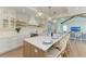 Bright kitchen with island featuring barstool seating, a modern range hood, and a seamless transition to the living area at 215 83Rd St, Holmes Beach, FL 34217