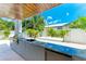 Outdoor kitchen with a sink, grill, and ping pong table, set against a backdrop of tropical greenery at 215 83Rd St, Holmes Beach, FL 34217