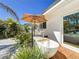 A backyard featuring an outdoor soaking tub, lounge chair under a sun umbrella, and lush greenery at 2308 Tulip St, Sarasota, FL 34239