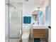 Bright bathroom featuring a modern vanity, round mirror, and a glass-enclosed shower with gold fixtures at 2308 Tulip St, Sarasota, FL 34239