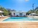 Back view of pool with wooden deck and white pool house with pink door surrounded by lush greenery at 2308 Tulip St, Sarasota, FL 34239