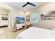 Bedroom with ceiling fan, picture window, and a guitar; a doorway leads to another room at 2322 5Th E St, Palmetto, FL 34221