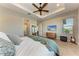 Bright main bedroom featuring tray ceilings, wood-look tile flooring, with entertainment center, ensuite bath and ceiling fan at 2322 5Th E St, Palmetto, FL 34221