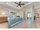Bright main bedroom featuring tray ceilings, wood-look tile flooring, and views of tropical landscaping through the windows at 2322 5Th E St, Palmetto, FL 34221