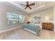 Bright main bedroom featuring tray ceilings, wood-look tile flooring, and views of tropical landscaping through the windows at 2322 5Th E St, Palmetto, FL 34221