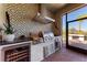Modern outdoor kitchen with stainless steel grill, wine cooler, decorative tile backsplash, and pizza oven at 2322 5Th E St, Palmetto, FL 34221
