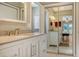 Bright bathroom featuring white cabinetry, quartz countertops, and mirrored closet at 2476 Breakwater Cir, Sarasota, FL 34231