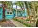 Cozy back porch with a wooden deck, surrounded by lush greenery and mature palm trees at 256 144Th Ave, Madeira Beach, FL 33708