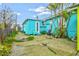Exterior shot of turquoise house featuring a back patio area with tropical landscaping at 256 144Th Ave, Madeira Beach, FL 33708