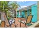 Inviting deck area with seating, surrounded by lush tropical landscaping and a turquoise home exterior at 256 144Th Ave, Madeira Beach, FL 33708