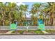 Bright blue home with palm trees, a white picket fence, and a whimsical gate featuring a sun design at 256 144Th Ave, Madeira Beach, FL 33708