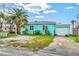View of the home's exterior with a white garage door, blue facade, and driveway with some greenery at 256 144Th Ave, Madeira Beach, FL 33708