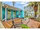 Inviting porch with chairs, plants and a door to welcome you to the bright turquoise home at 256 144Th Ave, Madeira Beach, FL 33708